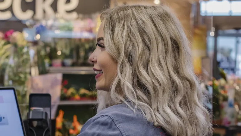 Eine REWE Mitarbeiterin sitzt an einer Kasse