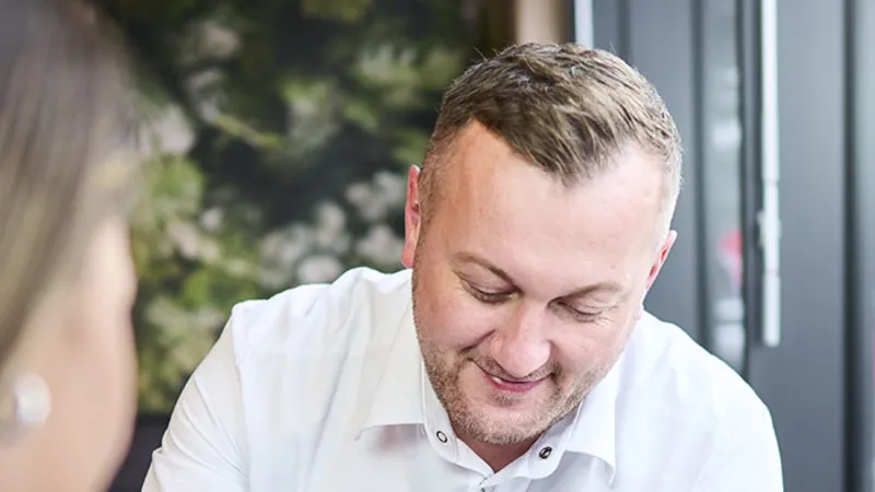 Ein REWE Mitarbeiter zeigt Produkte auf einem Handy