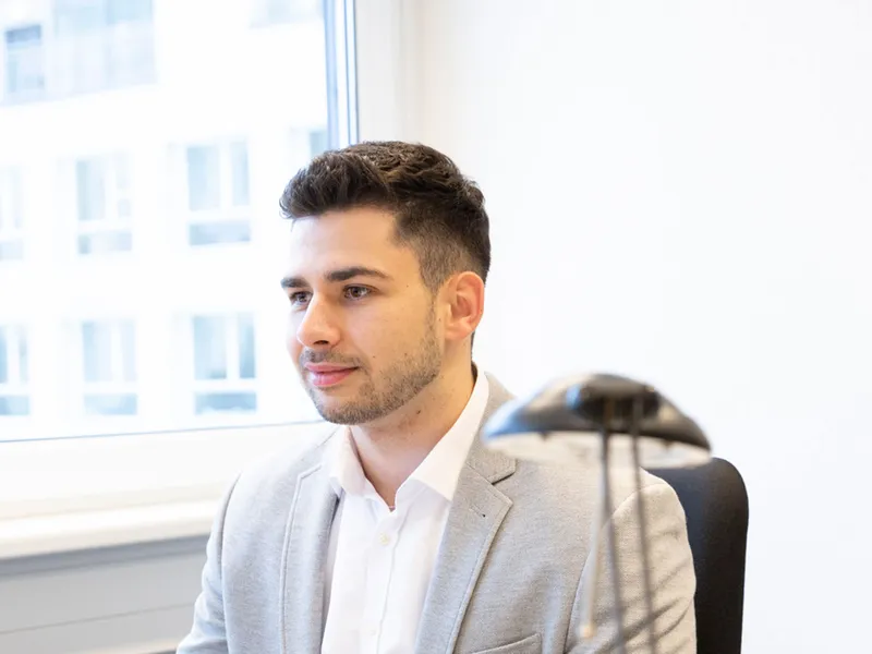 Ein REWE Auszubildender zum Kaufmann fuer Bueromanagement  sitzt an seinem Arbeitsplatz