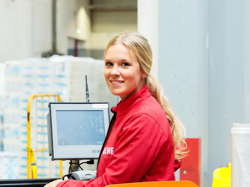 Eine duale REWE Studentin in der Logistik steht im Logistiklager