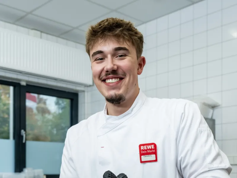 Ein REWE Auszubildender zum im Fleischer steht in der Fleischerei